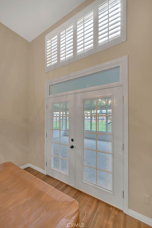 foyer entrance with wood finished floors, french doors, baseboards, and a healthy amount of sunlight