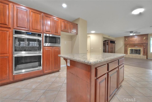 kitchen featuring a ceiling fan, light tile patterned flooring, light stone countertops, and stainless steel appliances