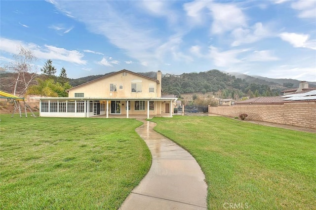 exterior space with a front lawn, fence, stucco siding, a chimney, and a sunroom