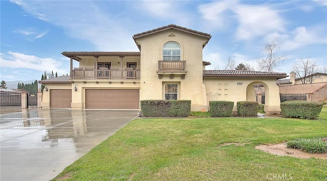 mediterranean / spanish-style house featuring a garage, stucco siding, a front lawn, and a balcony