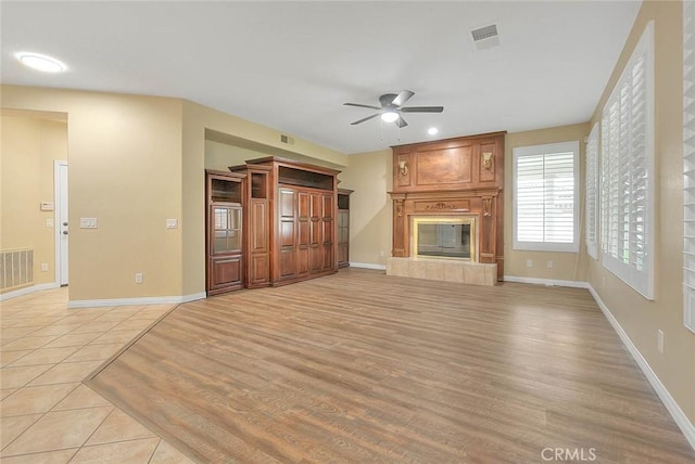 unfurnished living room featuring visible vents, baseboards, and a tiled fireplace