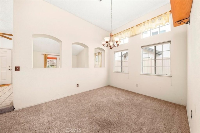 spare room with a chandelier, carpet, a wealth of natural light, and high vaulted ceiling