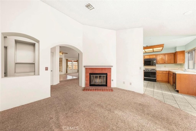 unfurnished living room featuring visible vents, a fireplace, light colored carpet, and arched walkways