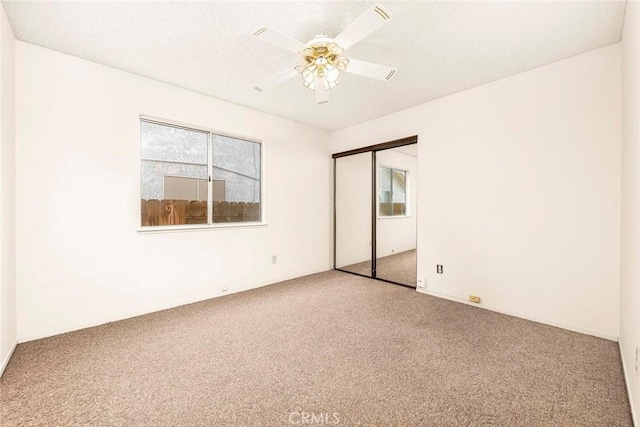 unfurnished bedroom featuring a closet, ceiling fan, a textured ceiling, and carpet