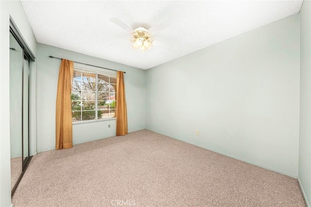 unfurnished bedroom featuring a textured ceiling, carpet flooring, a closet, and ceiling fan