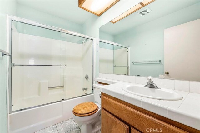 full bathroom featuring visible vents, toilet, shower / bath combination with glass door, tile patterned floors, and vanity