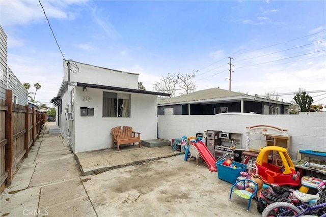 rear view of house with stucco siding, a patio, and fence private yard