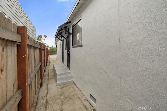 view of side of home featuring stucco siding and fence