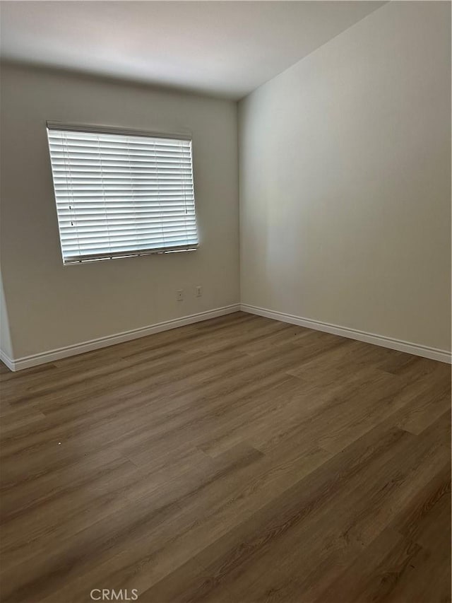 spare room with dark wood-style floors and baseboards