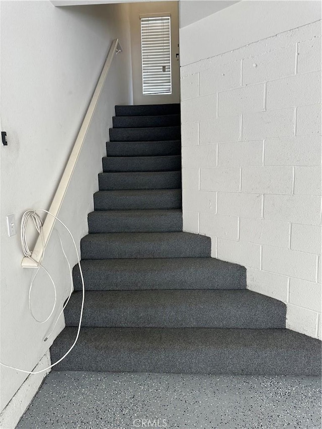 staircase with concrete block wall and speckled floor