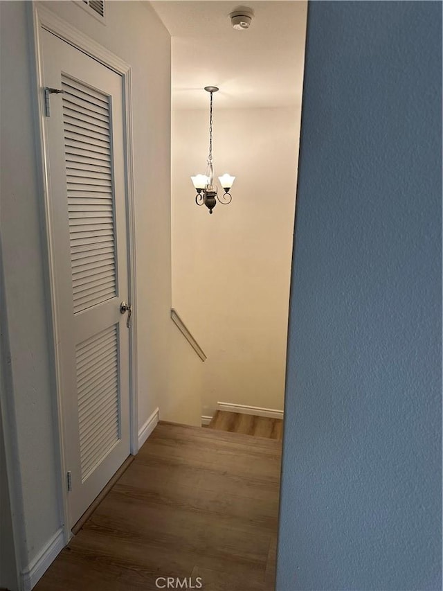 staircase with a chandelier and wood finished floors