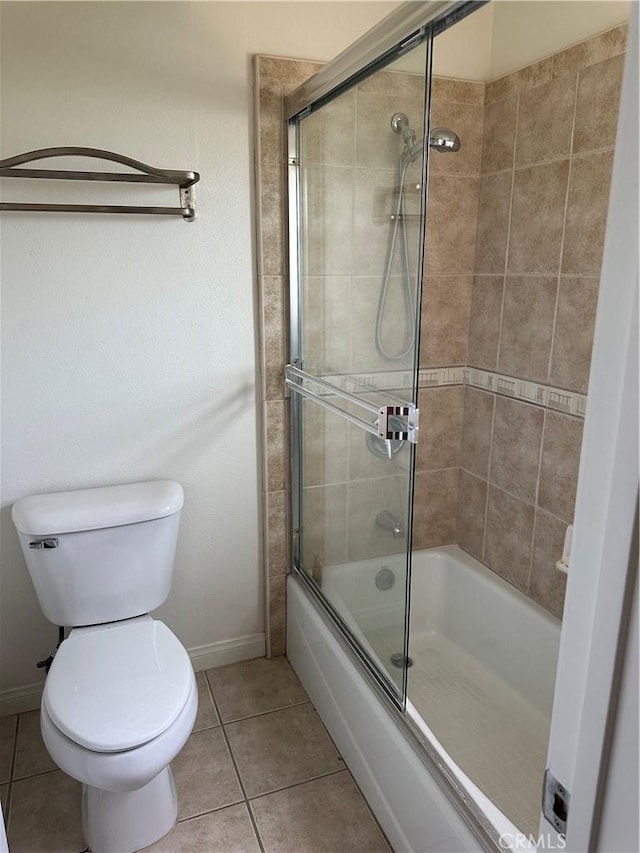 bathroom featuring tile patterned flooring, toilet, baseboards, and combined bath / shower with glass door