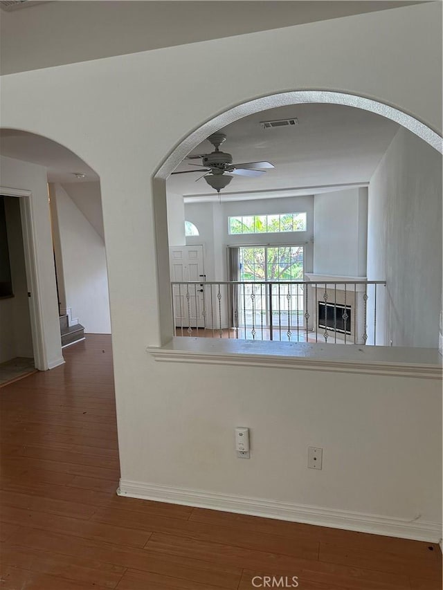 spare room featuring baseboards, wood finished floors, arched walkways, and ceiling fan