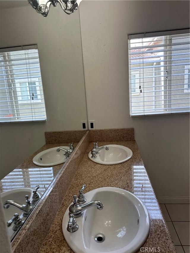 full bath with a sink, double vanity, and tile patterned flooring