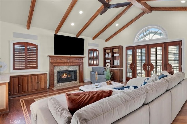 living area with a ceiling fan, high vaulted ceiling, wood finished floors, and a fireplace