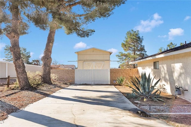 view of front of property with a storage unit, an outbuilding, a fenced backyard, and stucco siding