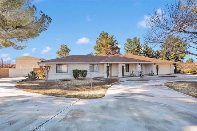 ranch-style house with stucco siding, concrete driveway, a garage, and fence