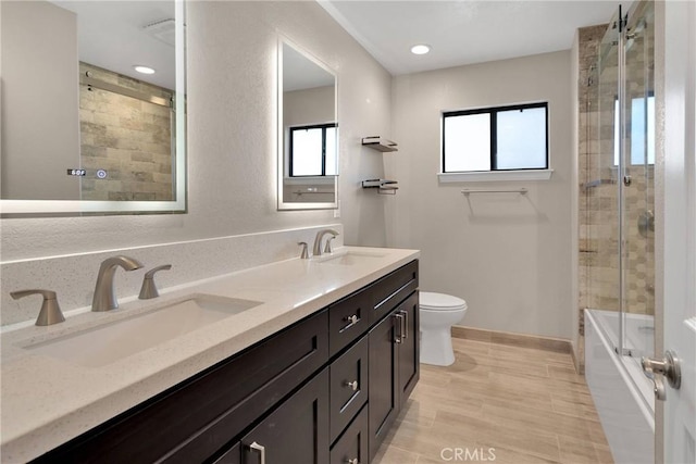 full bathroom featuring a sink, baseboards, toilet, and double vanity