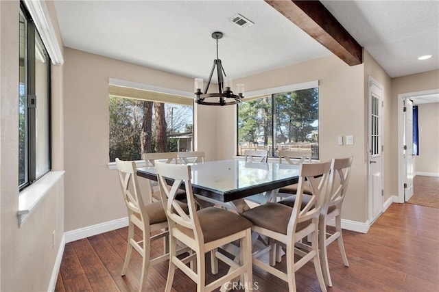 dining space with visible vents, beamed ceiling, hardwood / wood-style flooring, an inviting chandelier, and baseboards