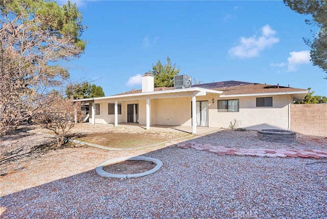 back of property with a patio, fence, central AC, a chimney, and stucco siding