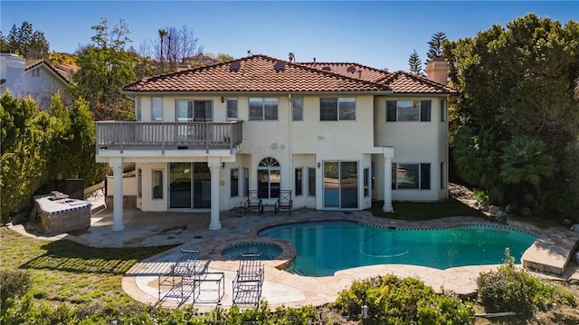 back of house with a patio, a balcony, a pool with connected hot tub, and a chimney