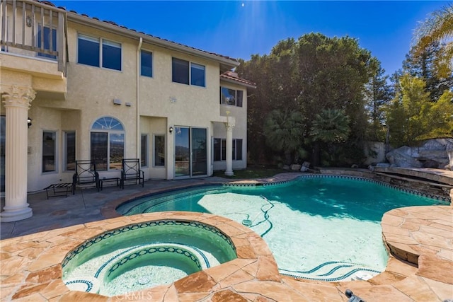 outdoor pool with a patio area and an in ground hot tub