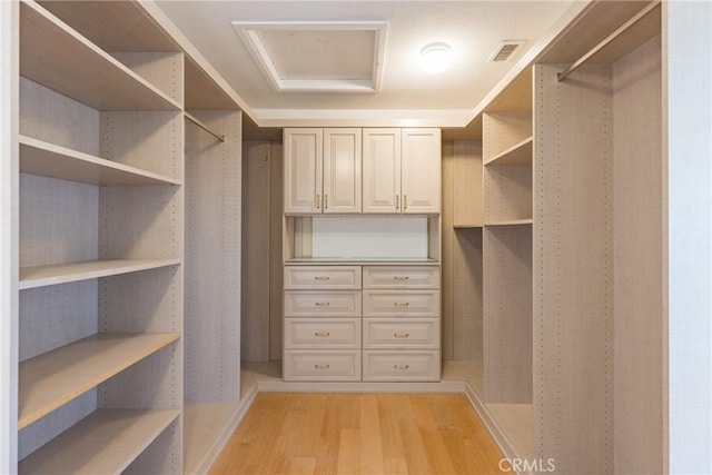 walk in closet featuring visible vents, light wood-style flooring, and attic access