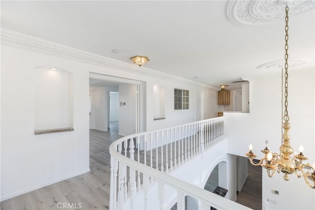 hallway featuring crown molding, a notable chandelier, wood finished floors, and baseboards