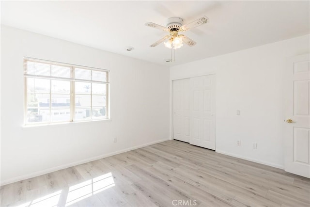 unfurnished bedroom featuring a closet, light wood-style flooring, a ceiling fan, and baseboards