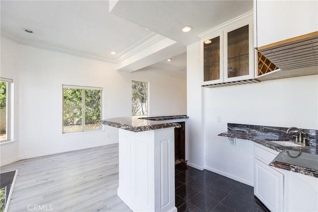 kitchen featuring a sink, dark stone counters, a wealth of natural light, and crown molding