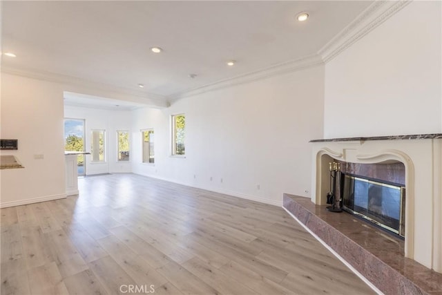 unfurnished living room featuring light wood-type flooring, a high end fireplace, and ornamental molding