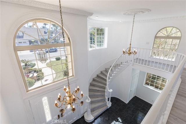 entrance foyer featuring an inviting chandelier, a high ceiling, stairway, and ornamental molding