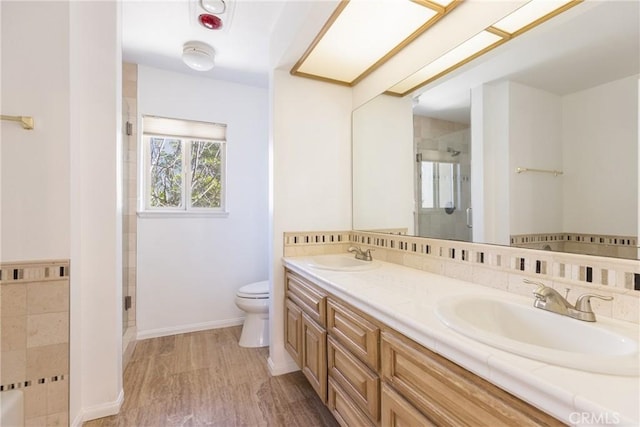 full bathroom with a shower stall, toilet, wood finished floors, and a sink