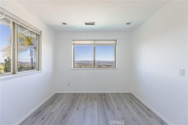 unfurnished room featuring a wealth of natural light, visible vents, and baseboards