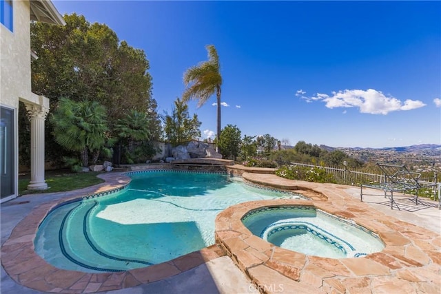 view of swimming pool featuring fence, a pool with connected hot tub, and a patio area