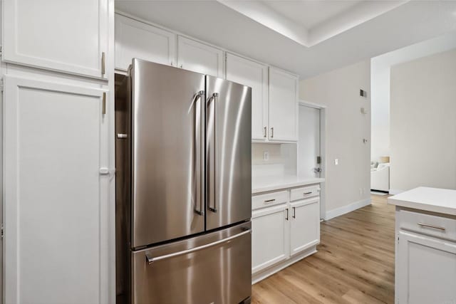 kitchen featuring light countertops, white cabinets, light wood-style floors, and freestanding refrigerator