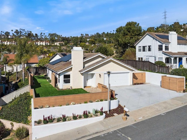 view of front of home featuring roof mounted solar panels, concrete driveway, a residential view, and fence