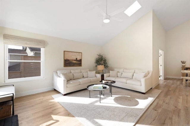 living area with light wood-style flooring, a skylight, baseboards, and a ceiling fan