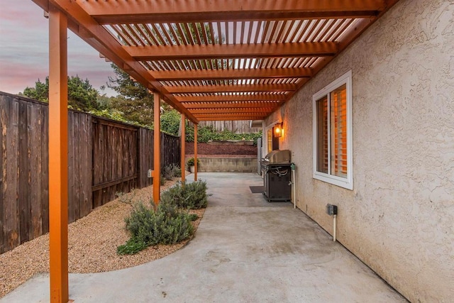 patio terrace at dusk featuring a grill, a fenced backyard, and a pergola