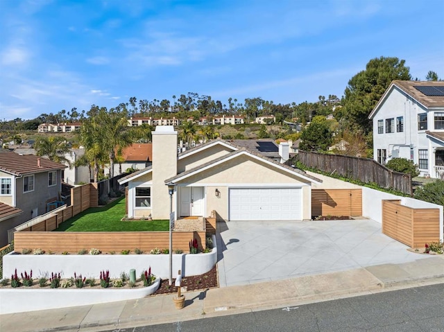 view of front facade featuring a fenced front yard, a residential view, an attached garage, and driveway