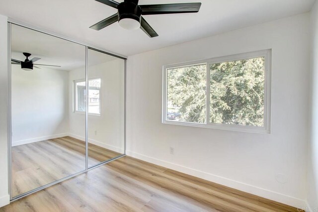 unfurnished bedroom featuring baseboards, light wood-type flooring, a closet, and ceiling fan