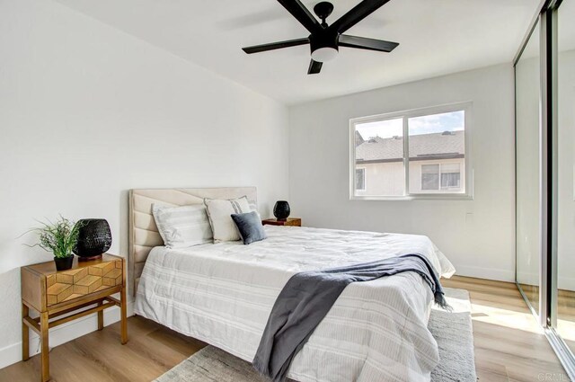 bedroom with a ceiling fan, baseboards, and wood finished floors