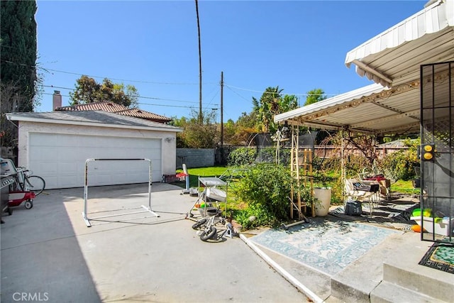 view of patio featuring an outbuilding, a garage, and fence