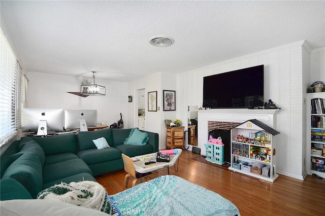 living area with a chandelier, visible vents, a textured ceiling, and wood finished floors