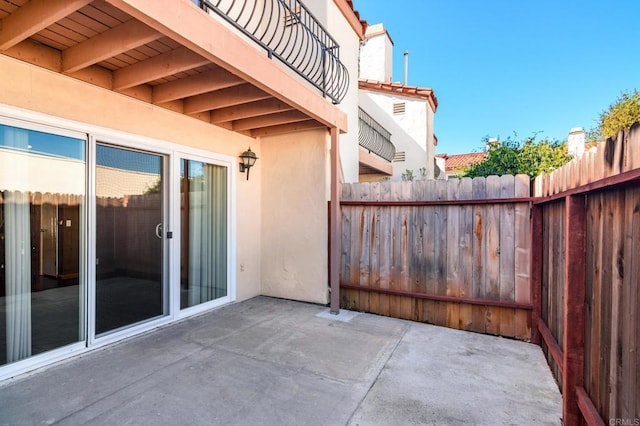 view of patio featuring a balcony and fence
