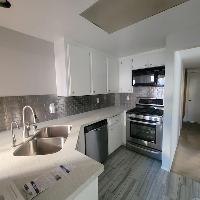 kitchen featuring a sink, stainless steel appliances, backsplash, and white cabinetry