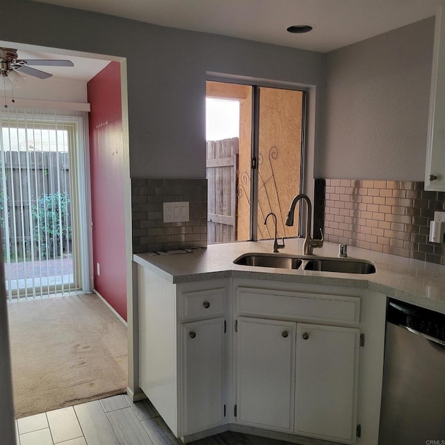 kitchen with dishwasher, light countertops, decorative backsplash, white cabinets, and a sink