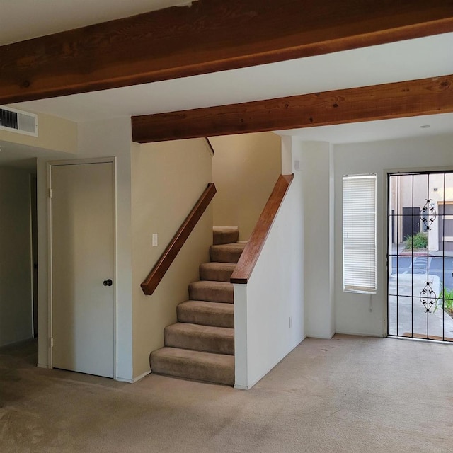 staircase featuring beamed ceiling, carpet, and visible vents