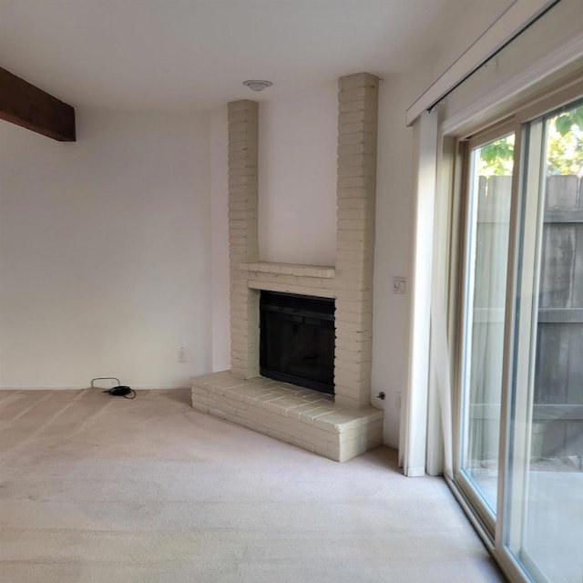 unfurnished living room featuring a brick fireplace and carpet flooring