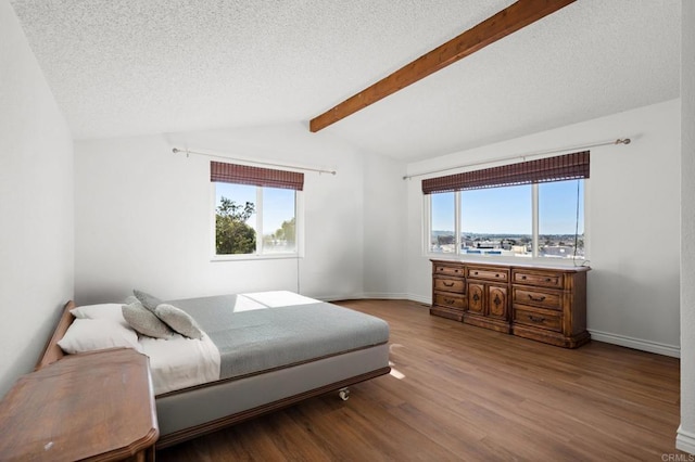 bedroom with a textured ceiling, vaulted ceiling with beams, baseboards, and wood finished floors